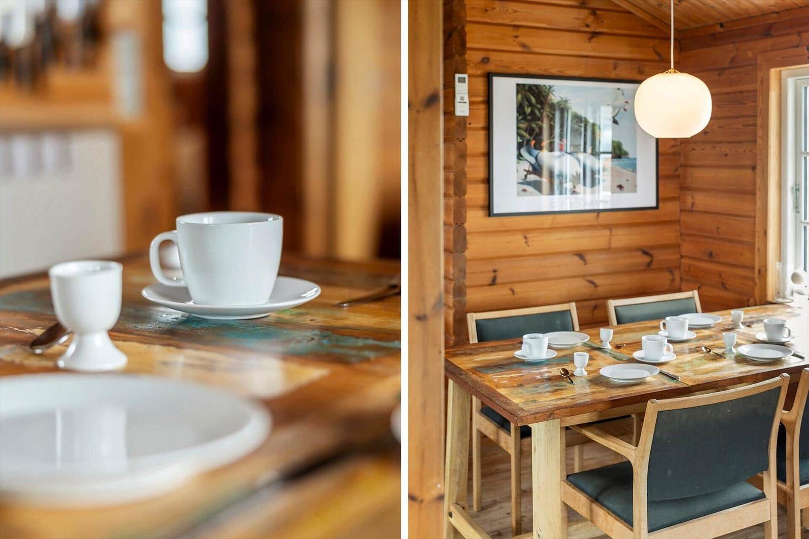 Holztisch mit Stühlen und Tischdecke in rustikalem Raum mit Wandbild und Pendelleuchte.
