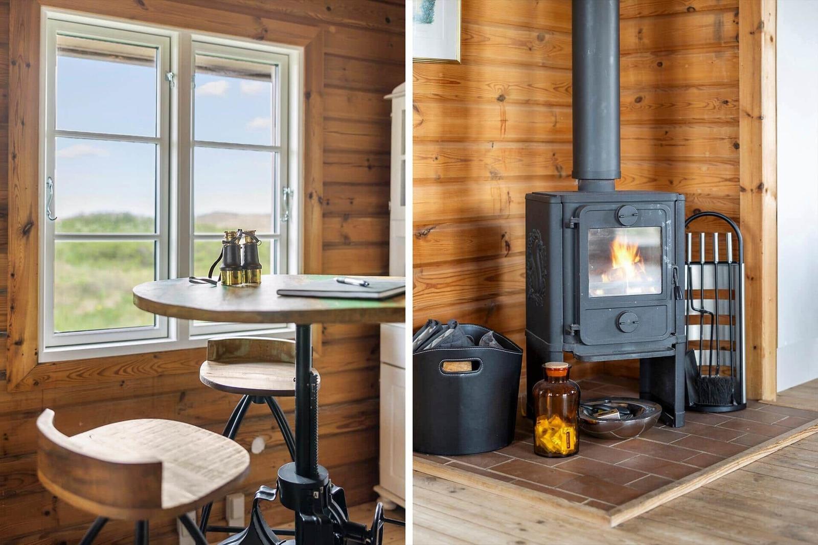 Holzhaus mit Tisch, Stühlen und Blick auf Landschaft. Kamin mit brennendem Feuer und Brennholz.