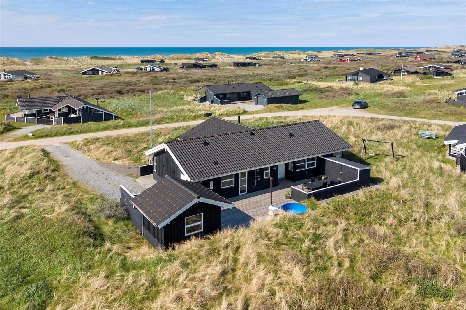 Modernes Ferienhaus mit Pool und Terrasse auf Dünenlandschaft mit Blick auf das Meer.