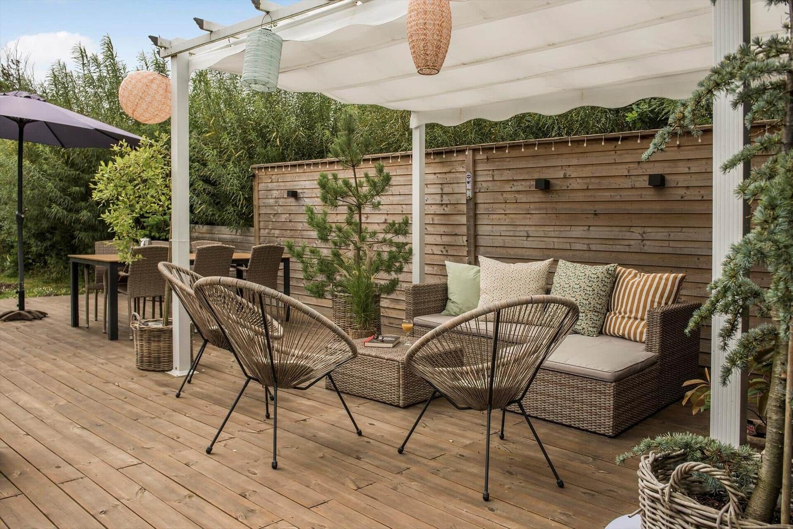 Terrasse mit Sitzgruppe, Tisch, Sonnenschutz und Pflanzen.