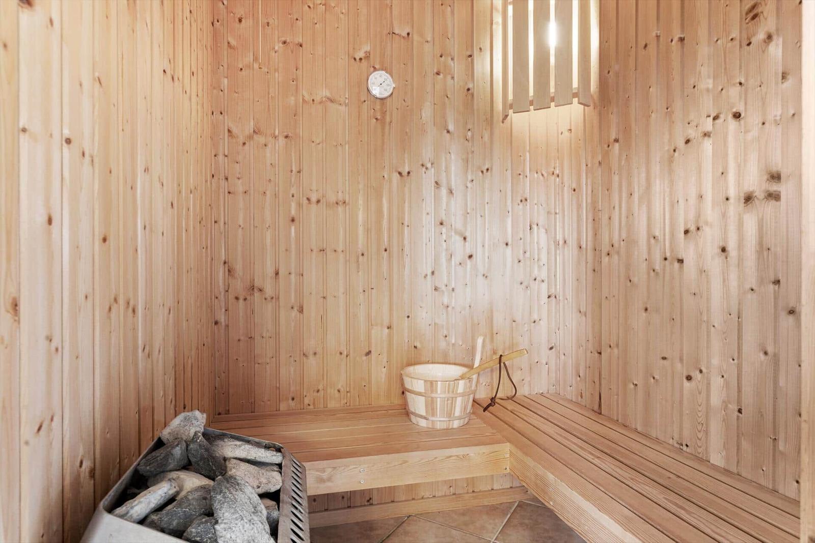Sauna mit Holzwand, Sitzbank, Eimer und Steine