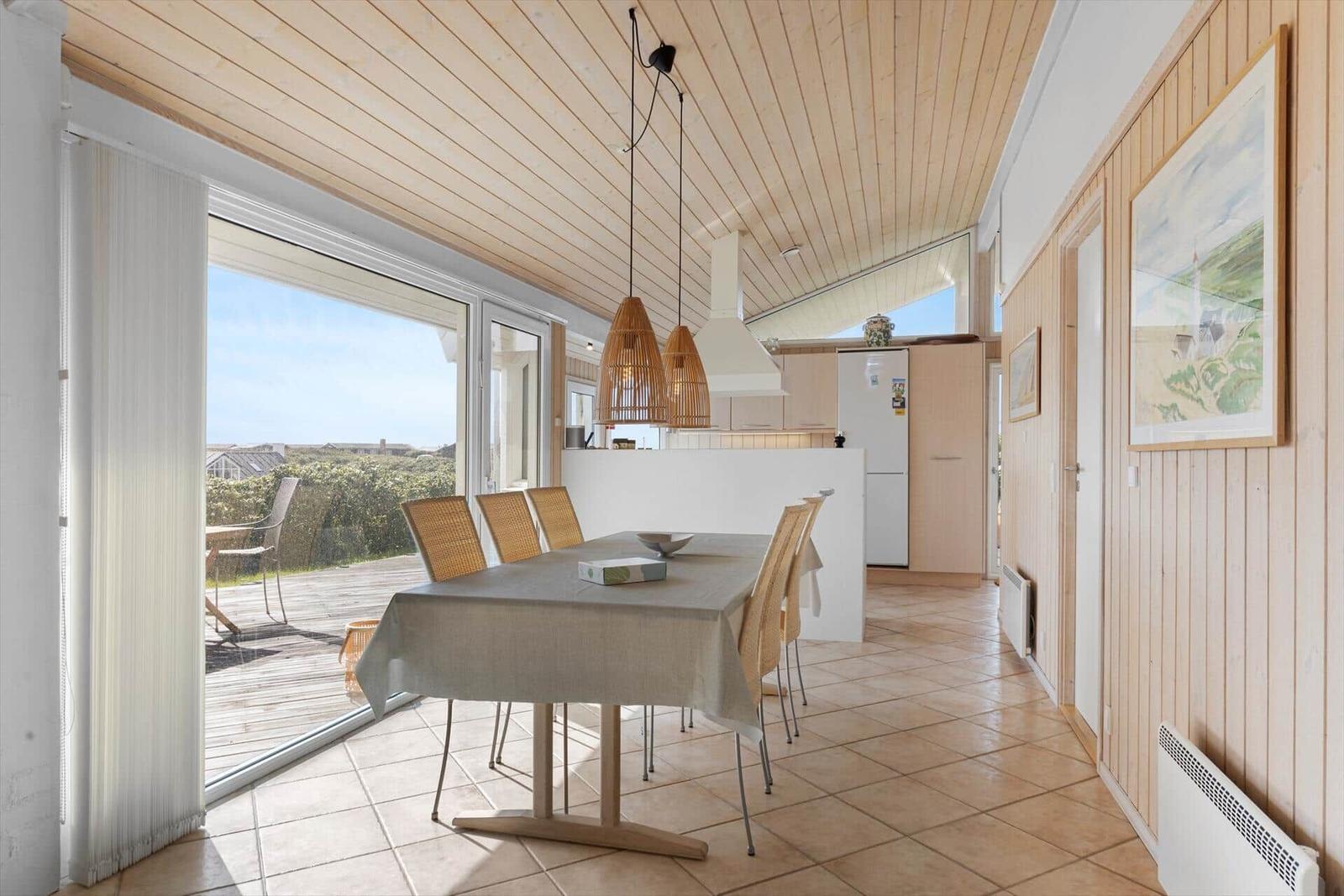 Essbereich mit Tisch und Stühlen, Blick auf Terrasse und Küchenbereich.