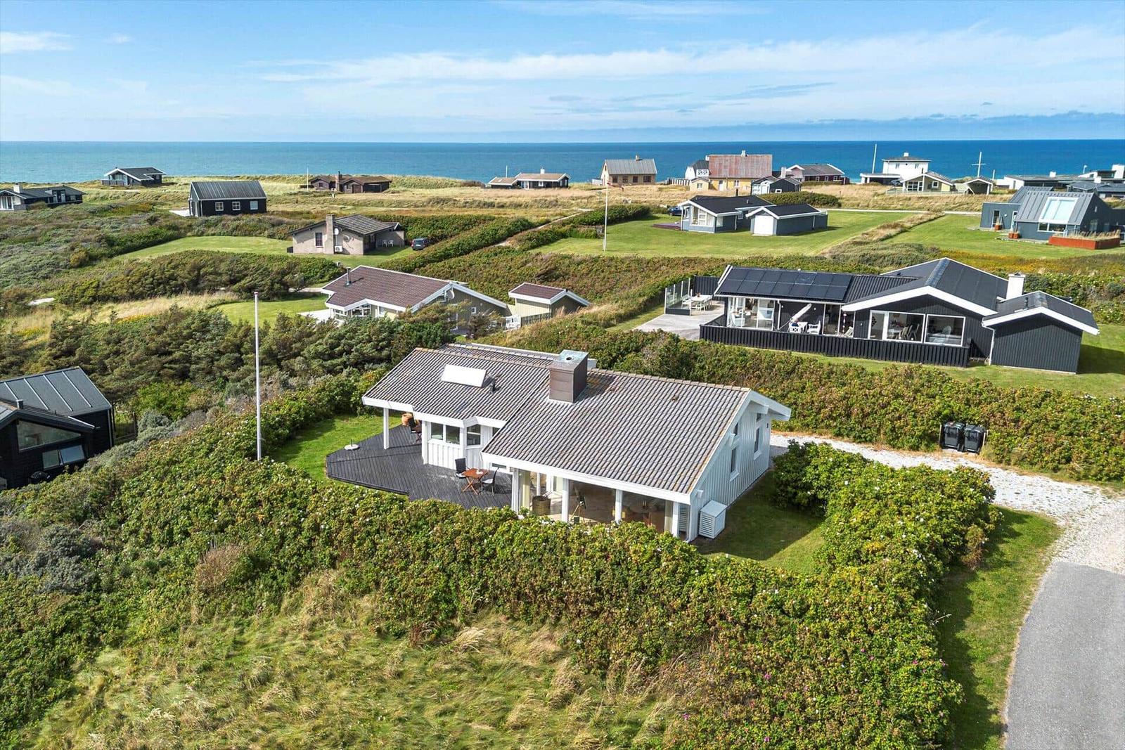 Moderne Villa mit Terrasse, umgeben von Grünflächen und Blick auf das Meer.