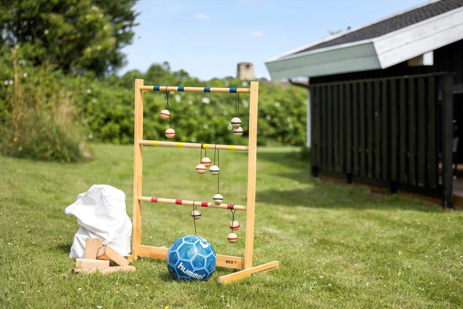 Holzspielgerät mit Kugeln und Ball auf Gras vor Haus