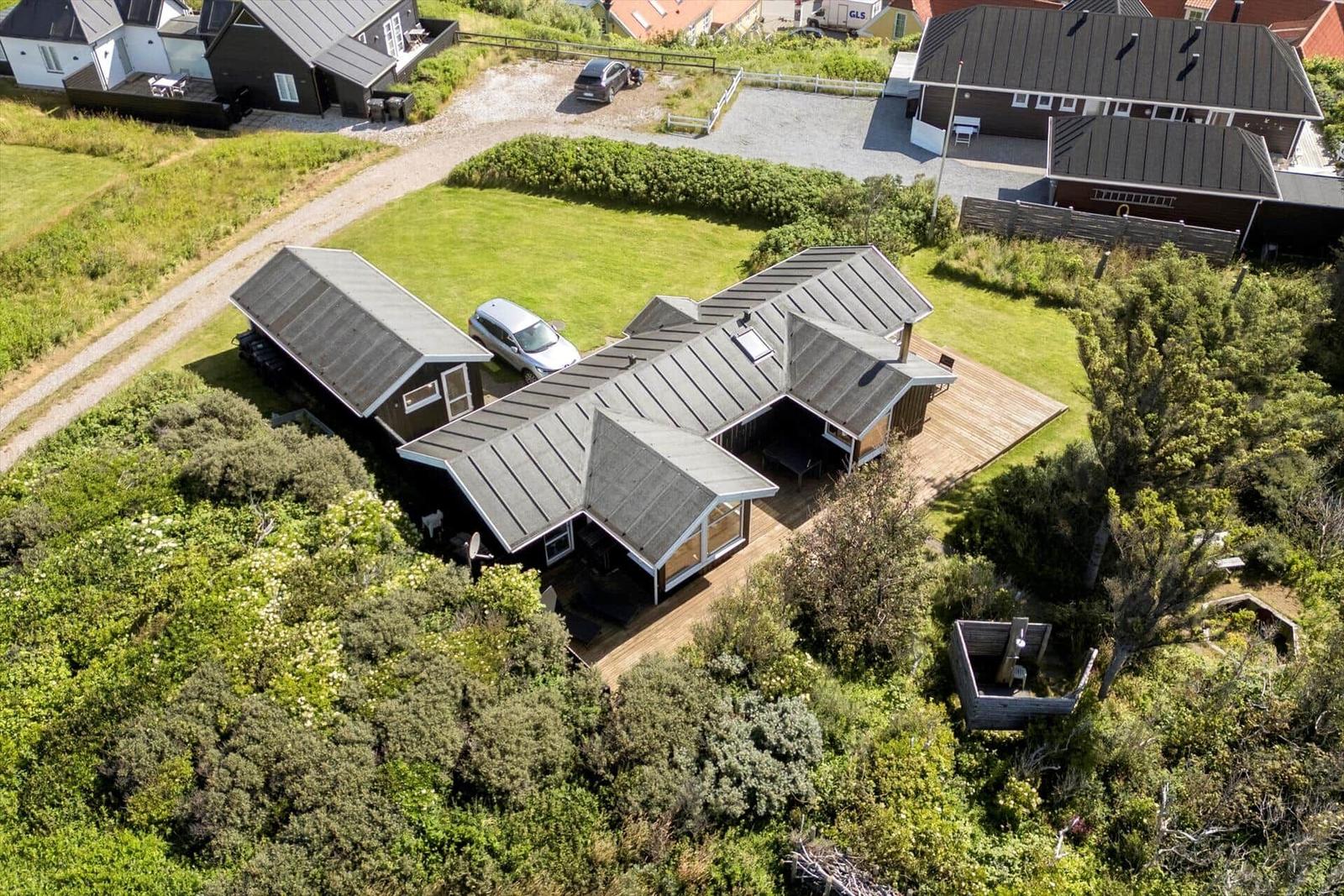 Modern holiday home with wooden terrace and green garden. Parking and forest surround.