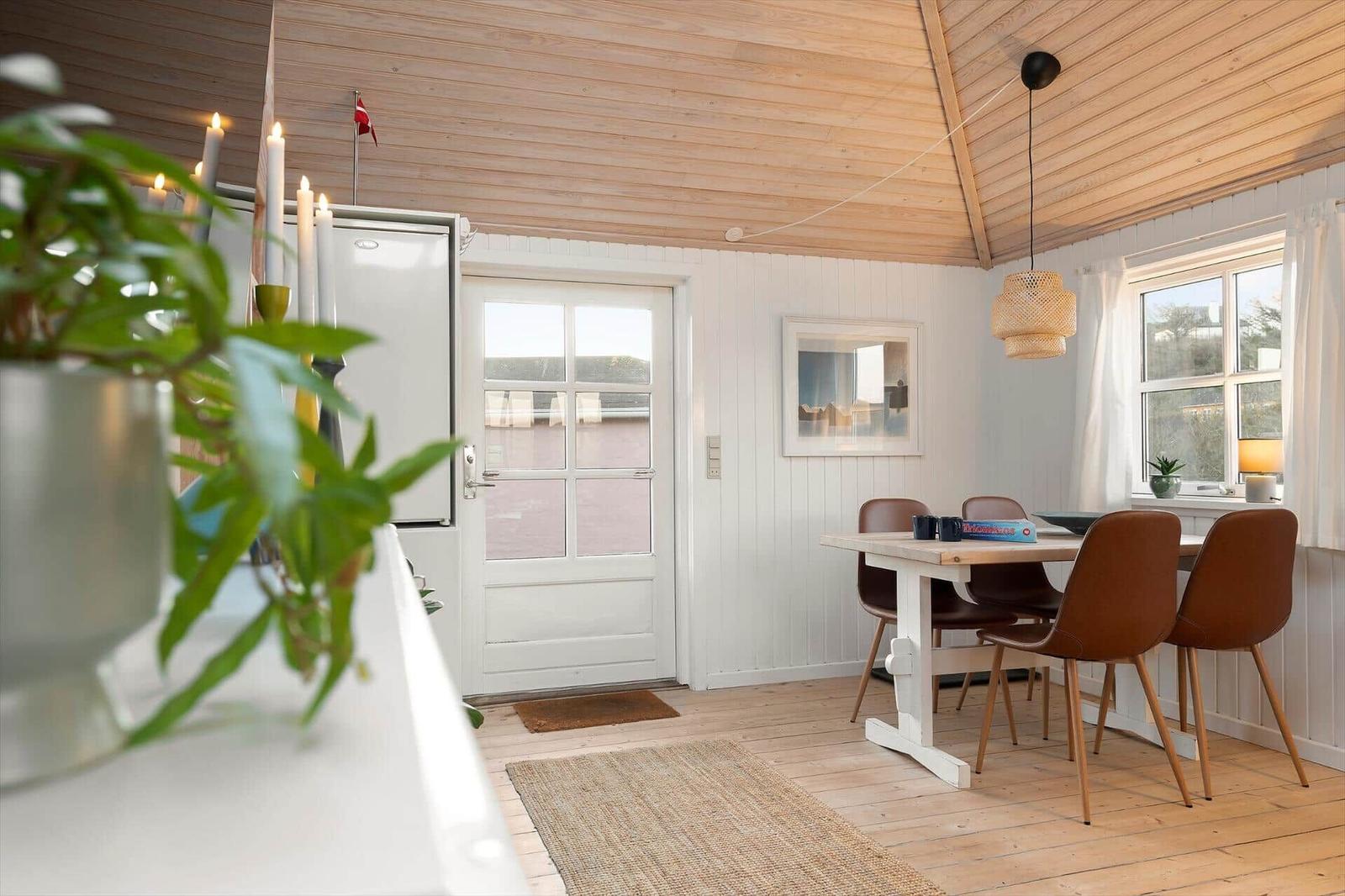 Küche mit Essbereich, Holzboden und weißen Wänden. Tisch mit braunen Stühlen und Fenster.