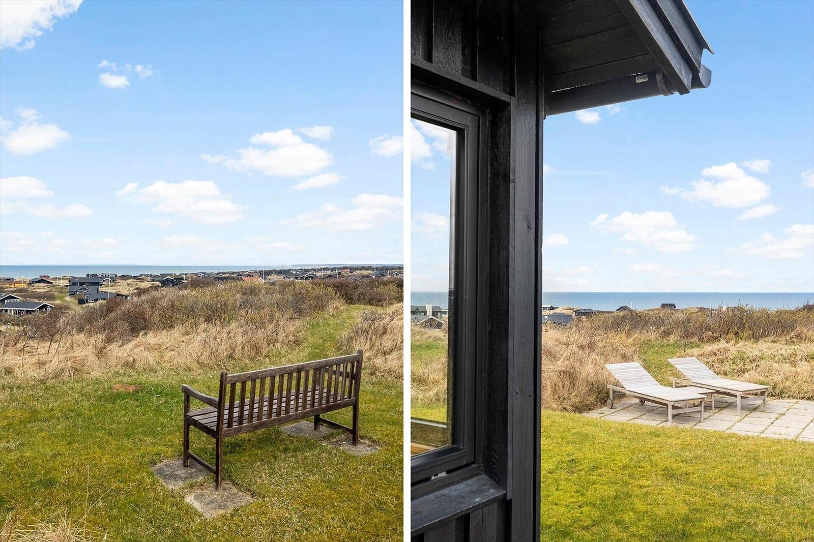 Ein Holzstuhl auf einer Wiese mit Blick auf das Meer. Durch ein Fenster sind zwei Liegestühle zu sehen.