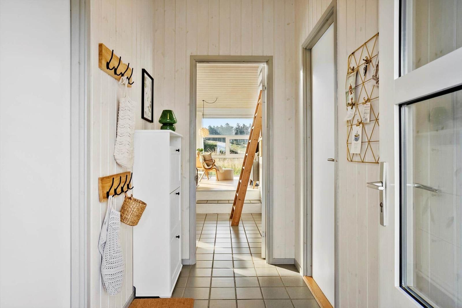 Flur mit Holzwand, Garderobe und Blick in Wohnbereich mit Treppe.