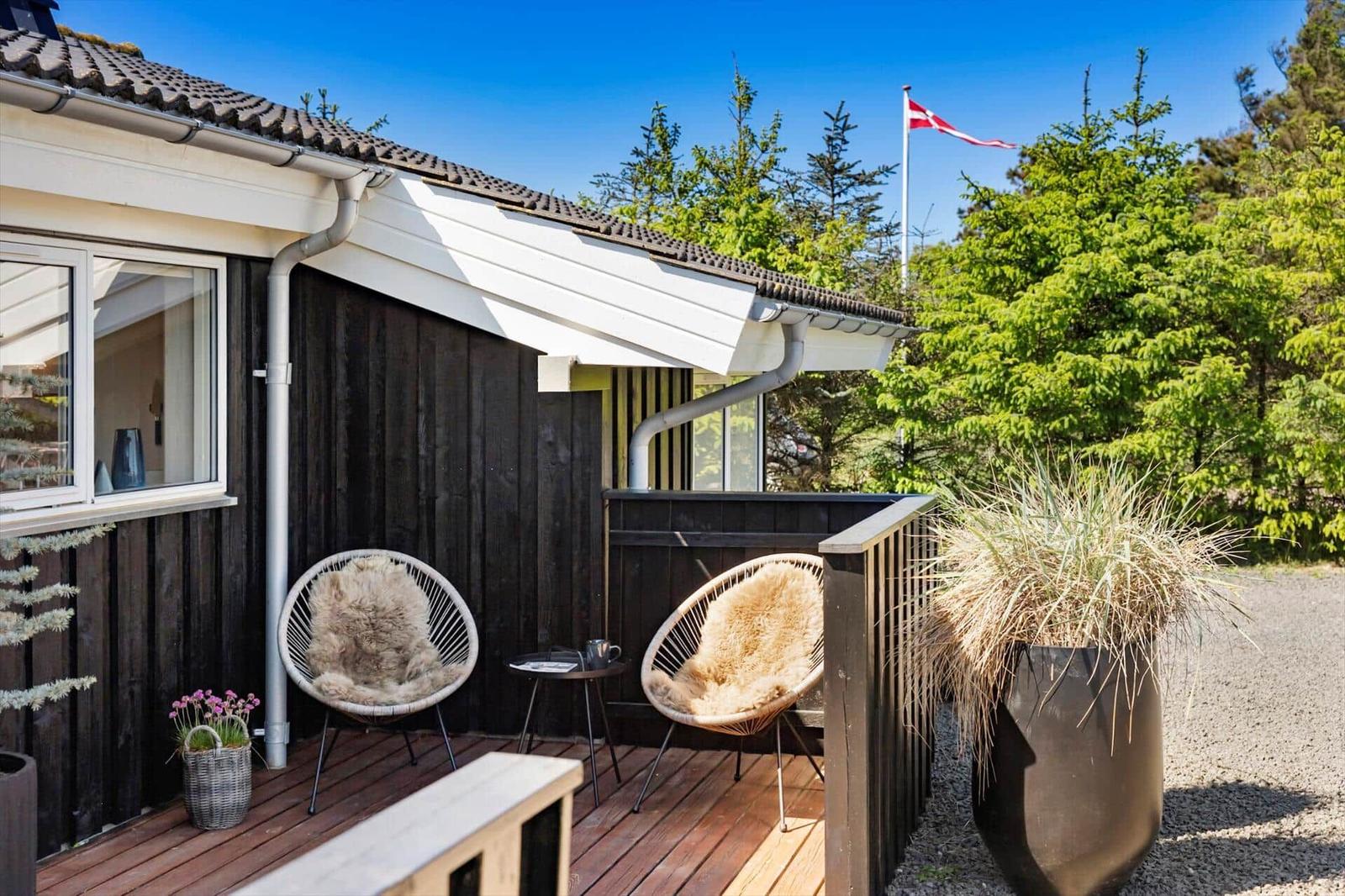 Terrasse mit zwei Stühlen, Pflanzen und dänischer Flagge im Hintergrund.