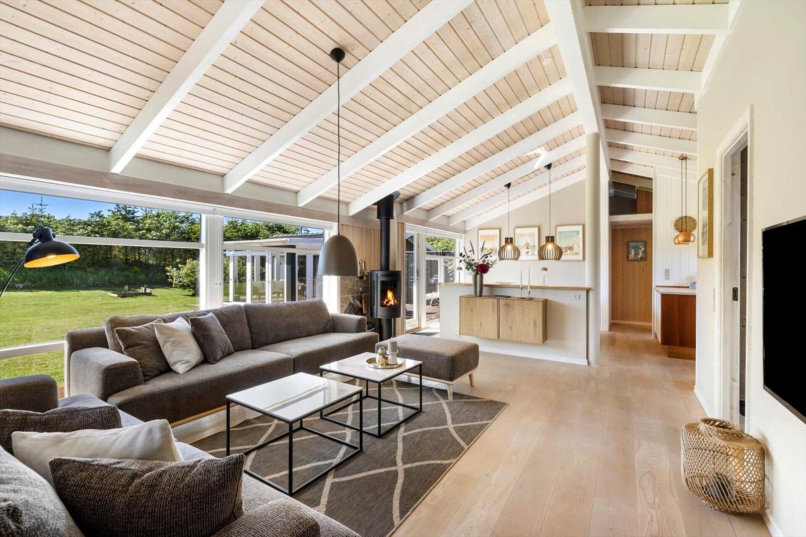Wohnbereich mit Sofa, Kamin und großem Fensterblick auf den Garten.