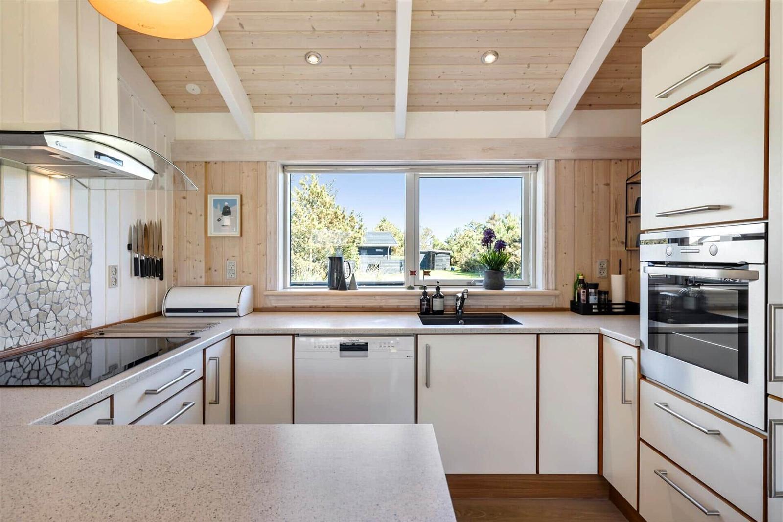 Küche mit Holzdecke, Fenster und modernen Geräten