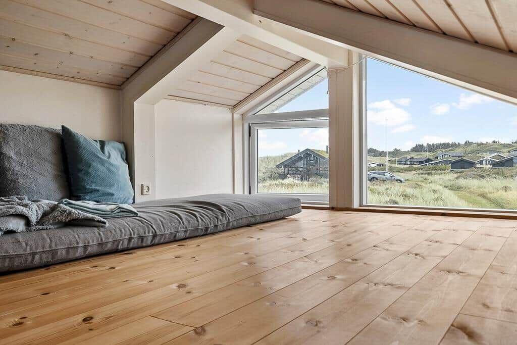 Raum mit Holzboden und großem Fensterblick auf die Landschaft.