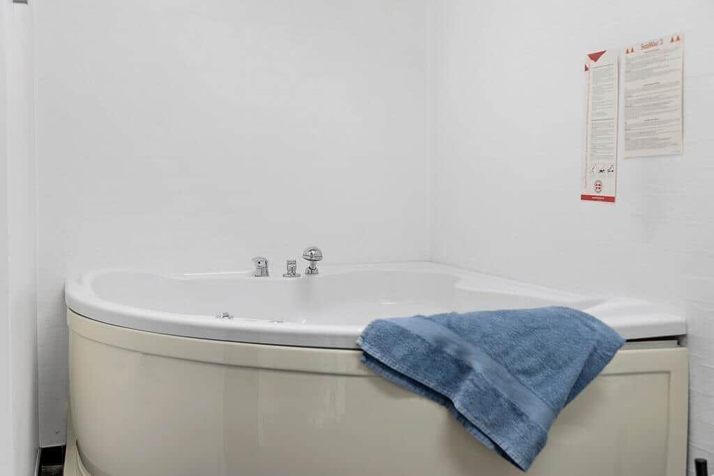 Eckbadewanne mit blauem Handtuch und Wandhinweisen