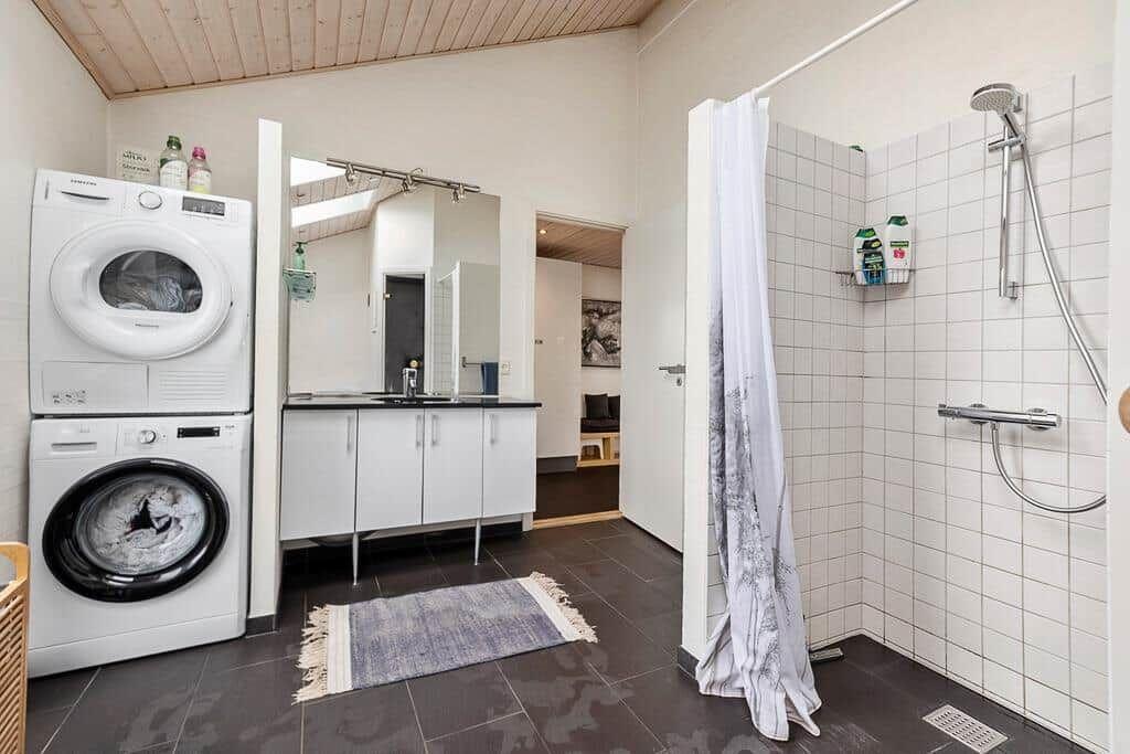 Badezimmer mit Dusche, Waschmaschine und Spiegelschrank