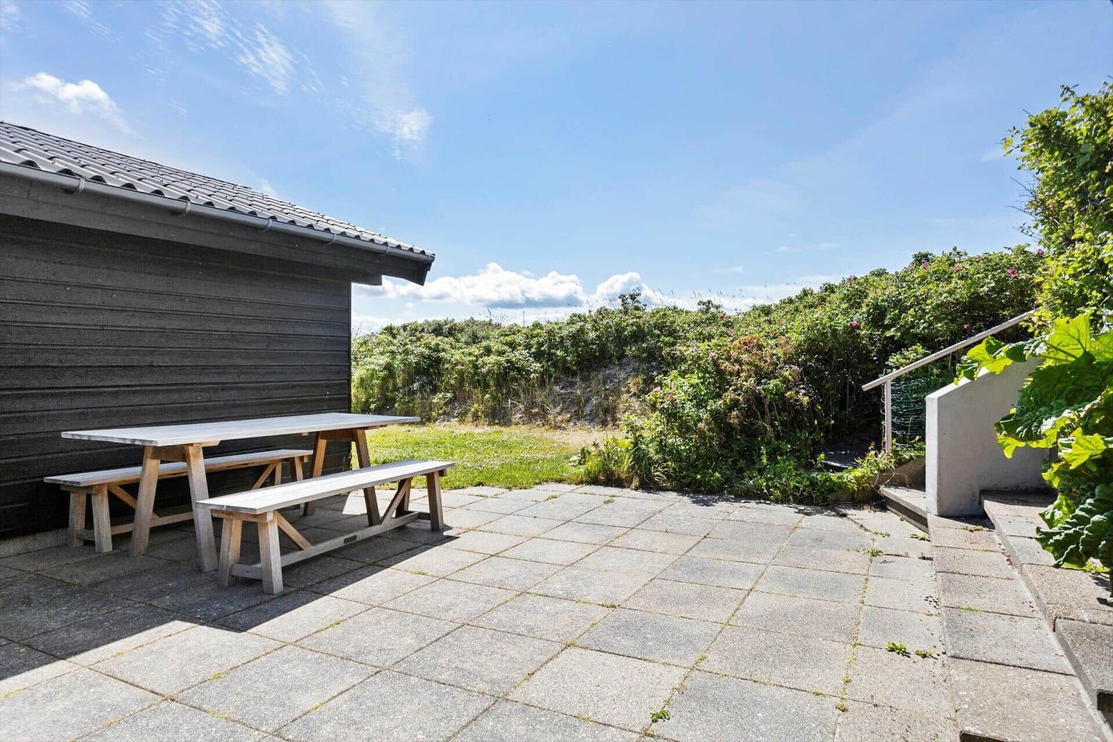 Terrasse mit Holztisch und Bänken neben einem Gebäude mit Holzfassade.