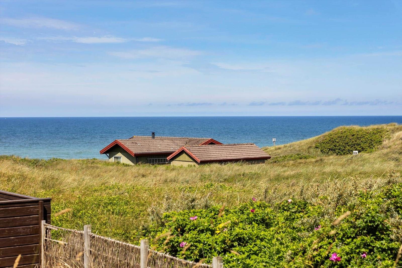 Haus auf Dünen mit Meerblick. Grasland und blauer Himmel.