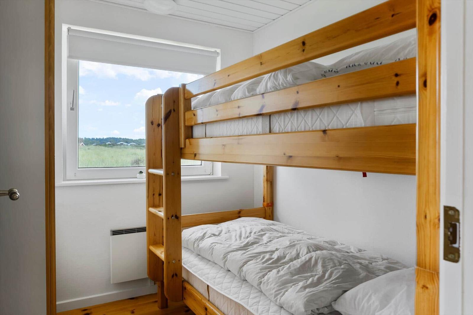 Zimmer mit Holz-Kinderbett und Fensterblick auf Grünland.