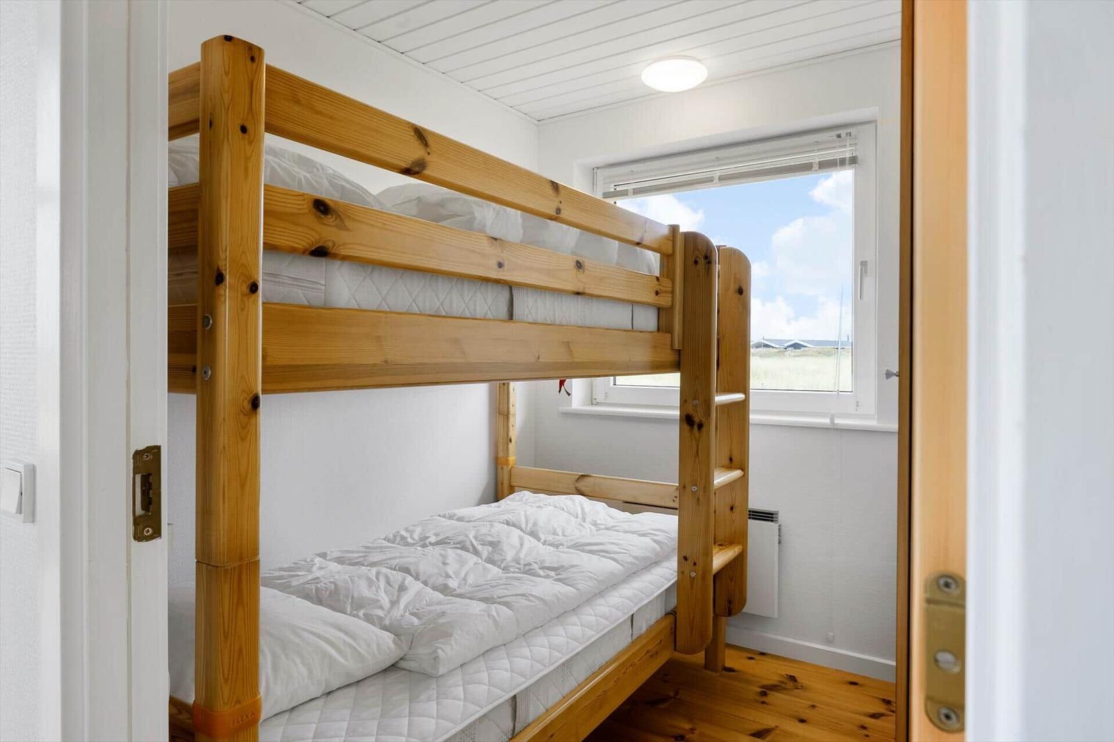 Zimmer mit Doppelstockbett und Fensterblick auf die Landschaft.