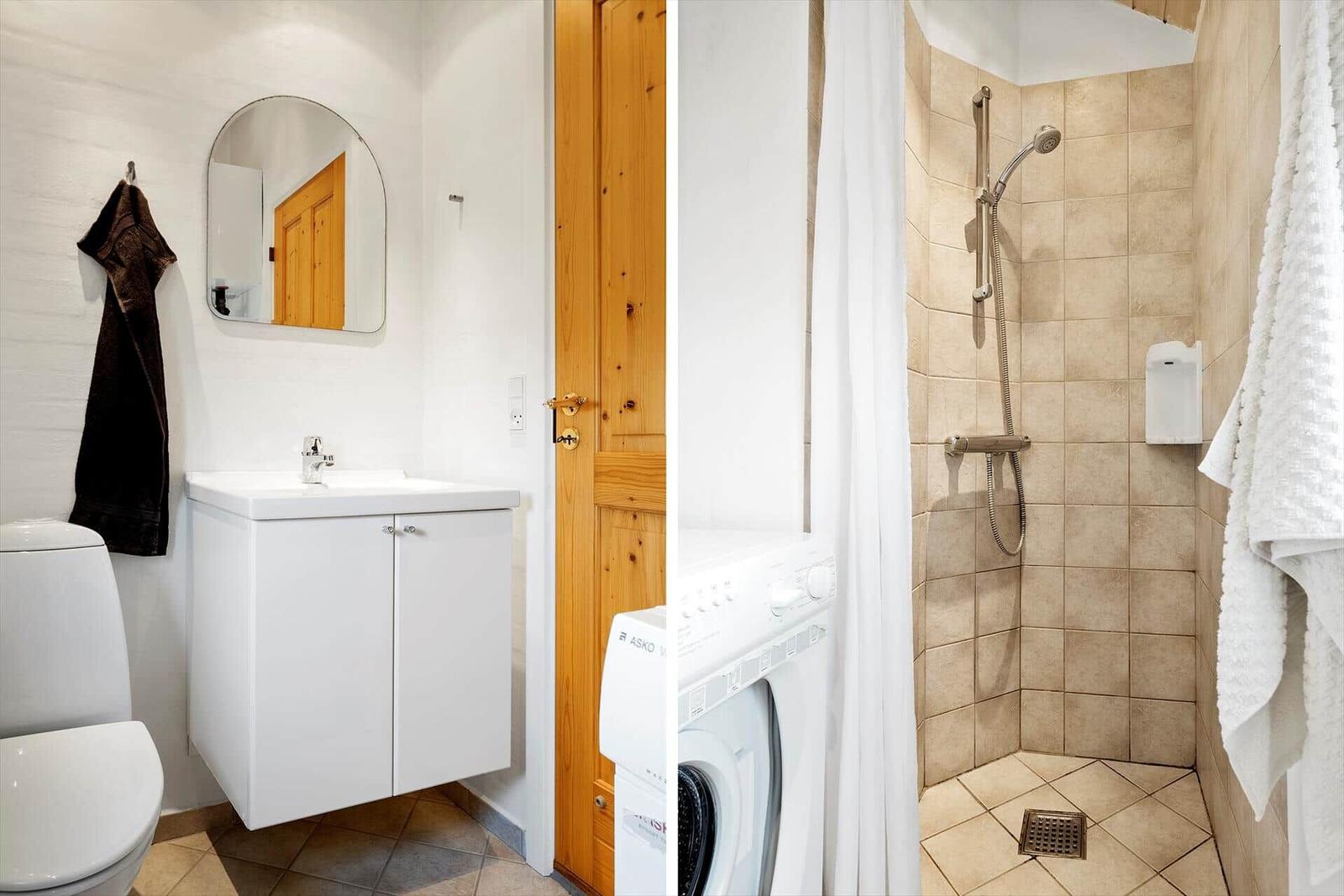Badezimmer mit Waschmaschine und Dusche. Fliesenwand, Spiegel und Toilette sichtbar.