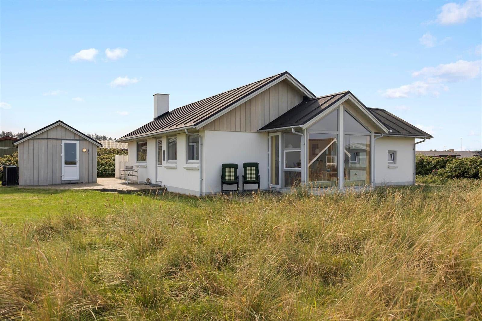 Moderne Ferienhaus mit Terrasse und Garten. Nebenhaus mit Tür.