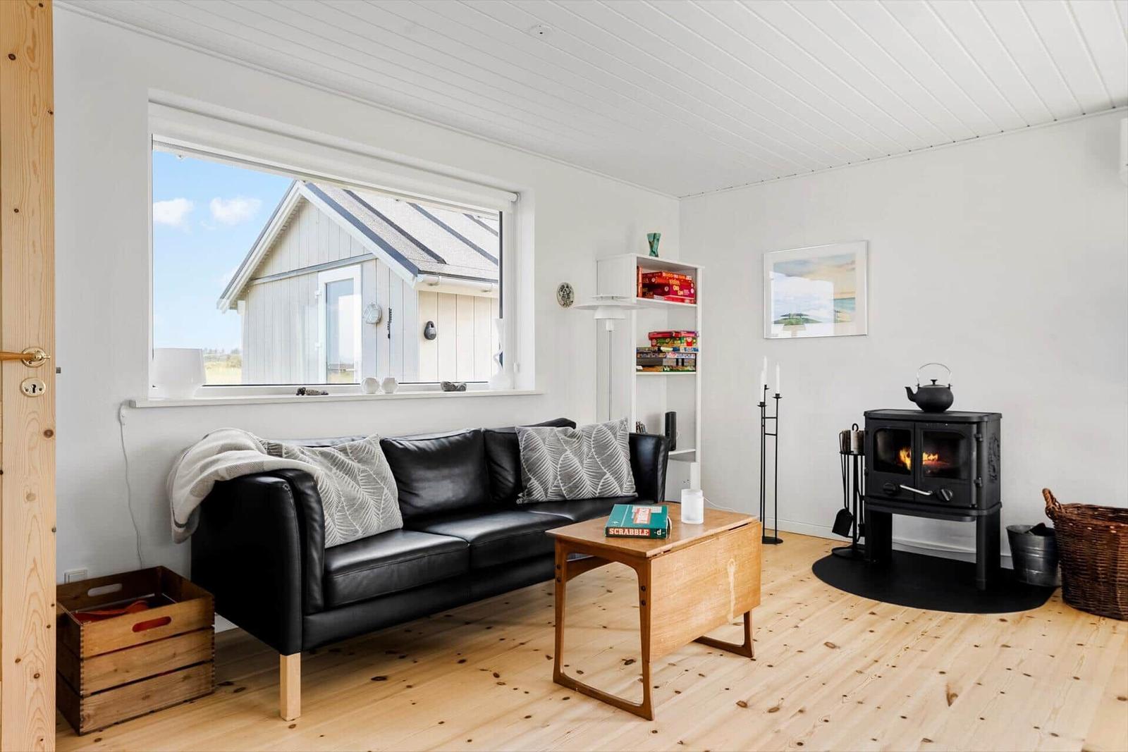 Wohnzimmer mit Sofa, Kamin und Fensterblick auf Haus
