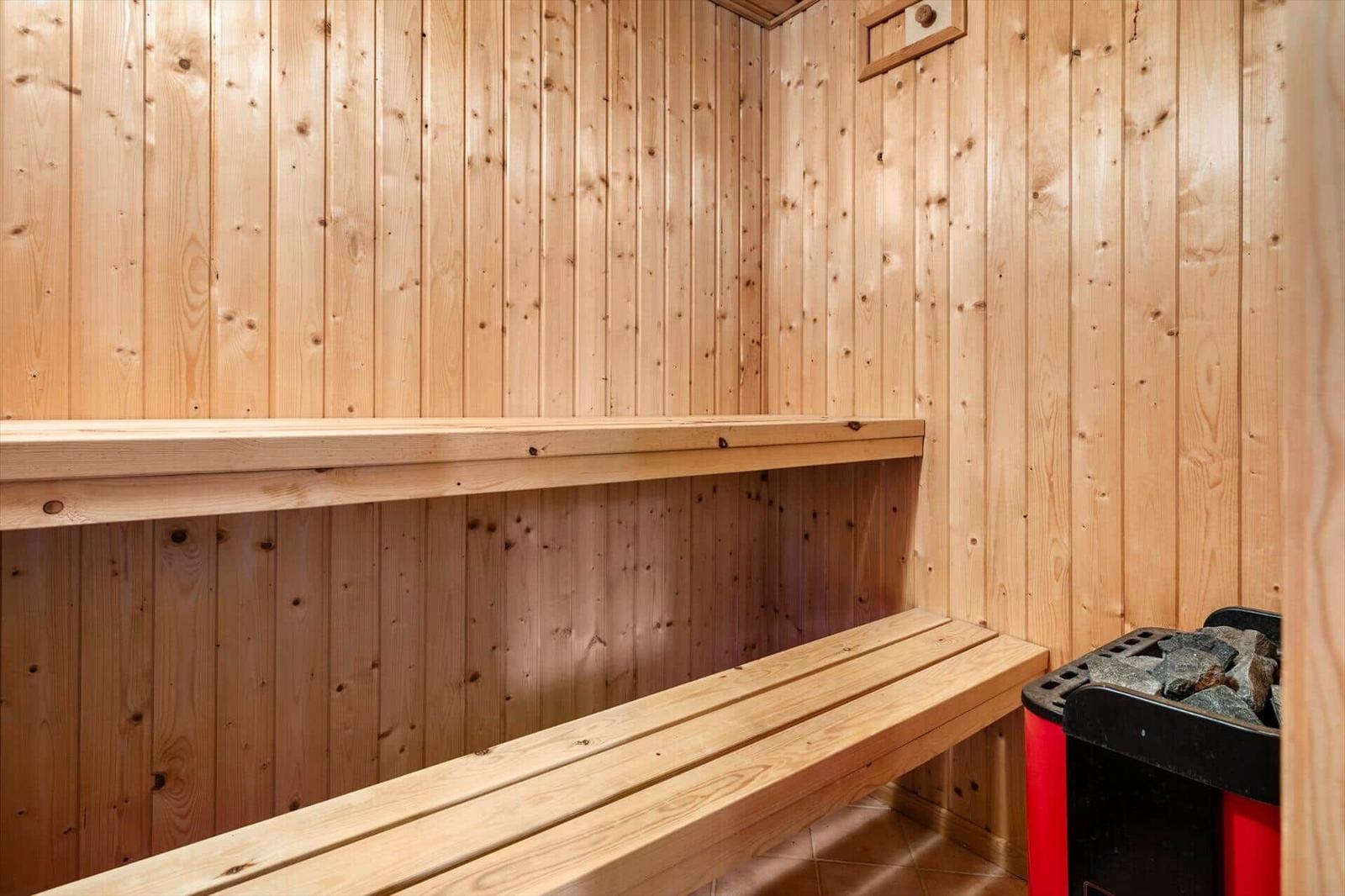 Sauna mit Holzwand und Sitzbänken. Heizung mit Steinen.
