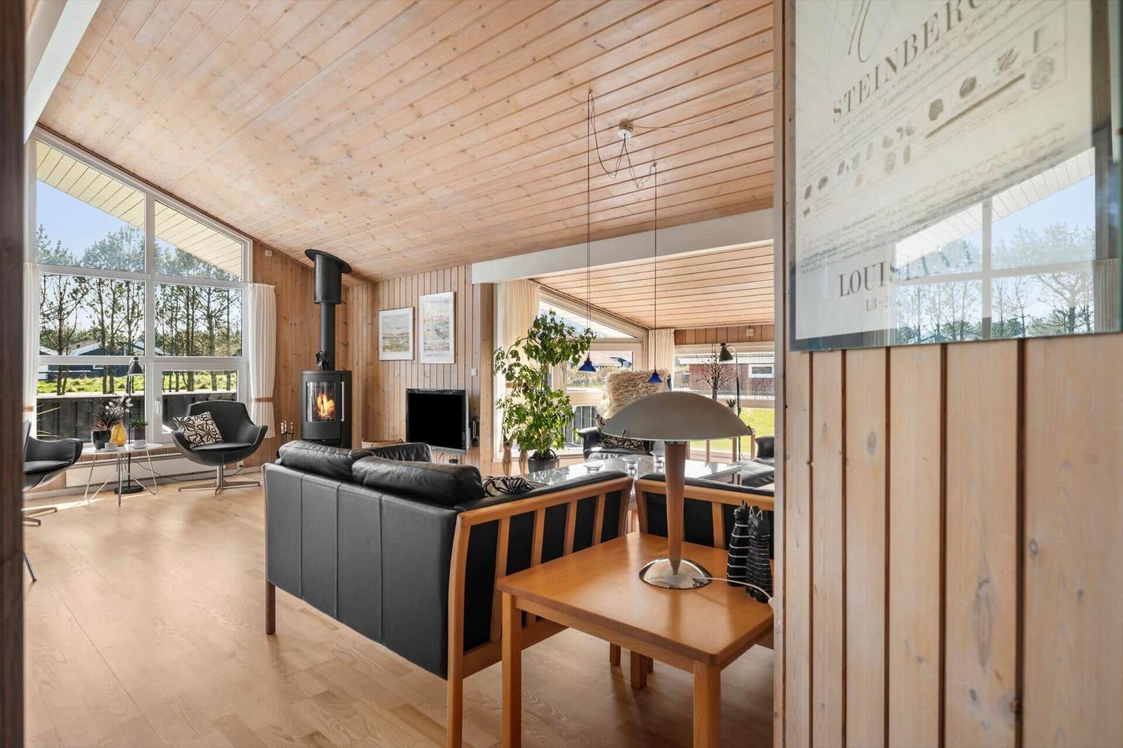 Wohnzimmer mit Holzdecke, Kamin und großem Fenster zur Aussicht.