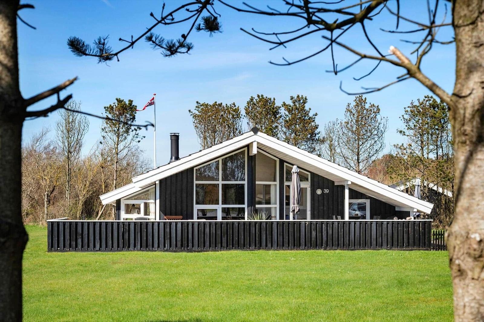 Moderne Villa mit großem Garten und Terrasse. Flagge weht im Wind.