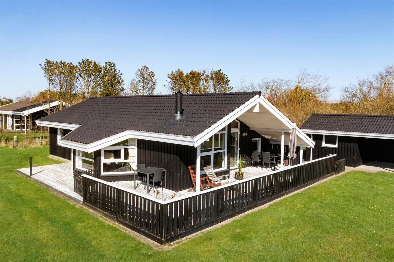 Moderne Villa mit Terrasse, Garten und Sitzgelegenheiten unter freiem Himmel.