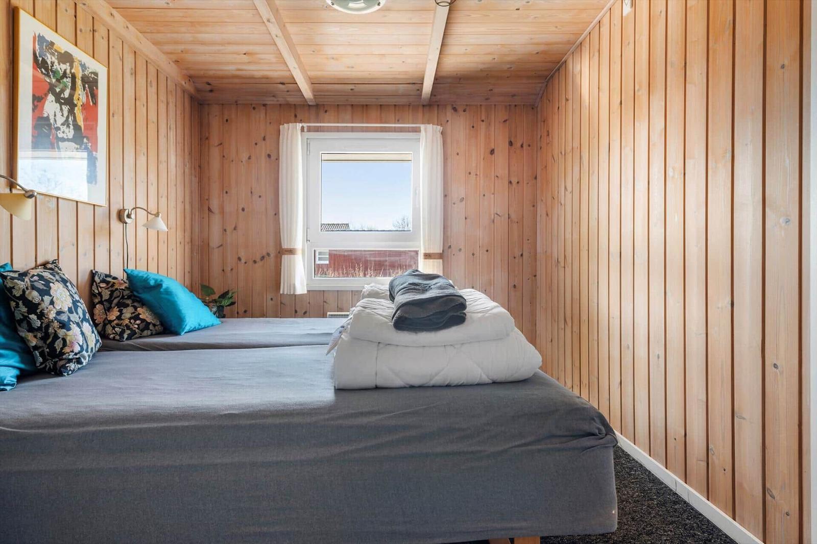 Ein Schlafzimmer mit Holzwänden, einem Bett und einem Fenster.