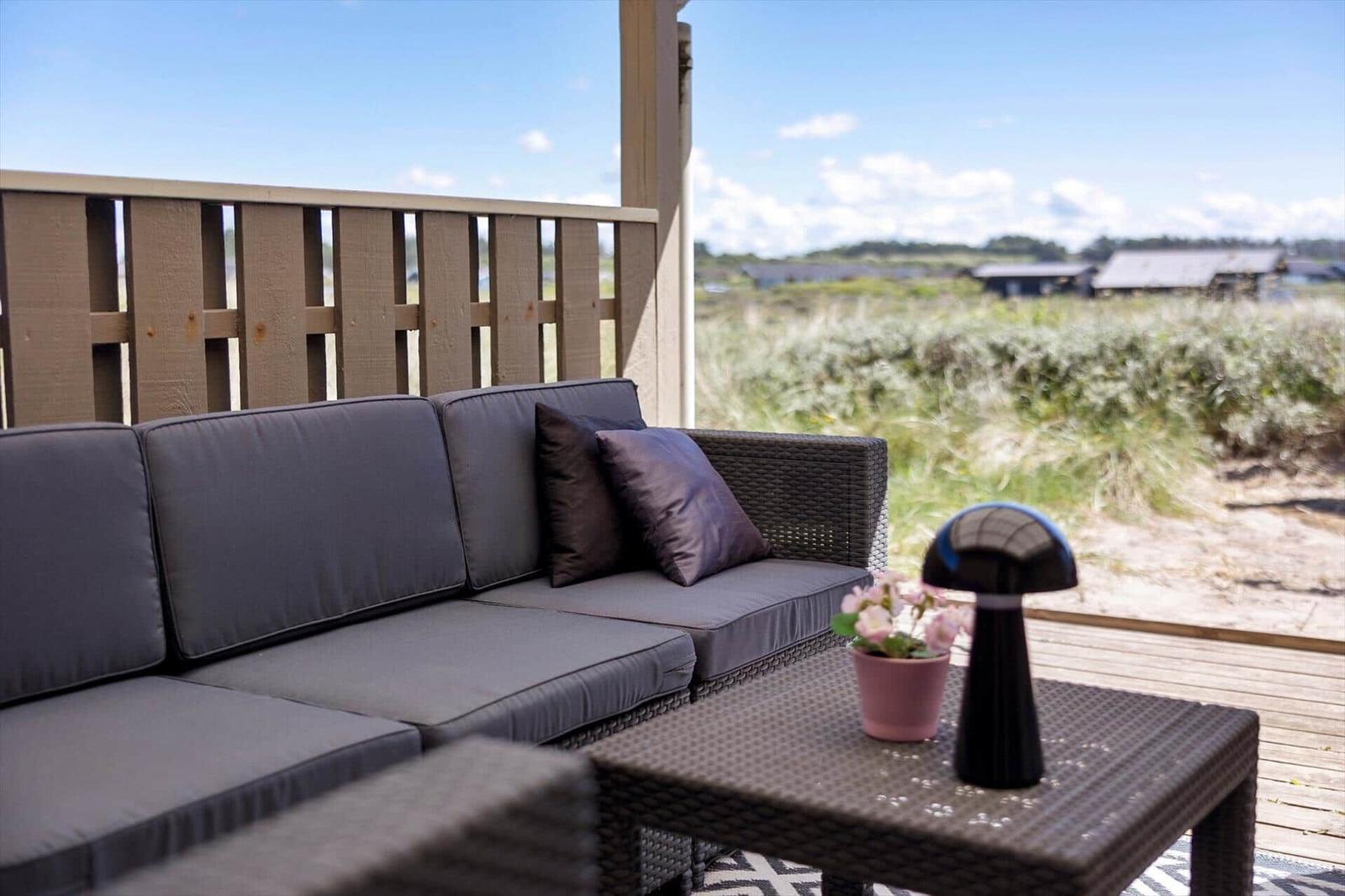 Terrasse mit Sofa, Tisch und Blick auf Grasland.