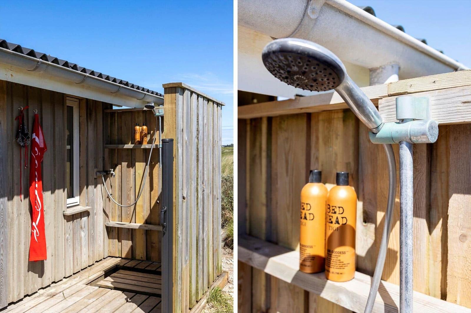 Außen-Dusche mit Duschbrause und zwei orangefarbenen Flaschen auf Holzregal.