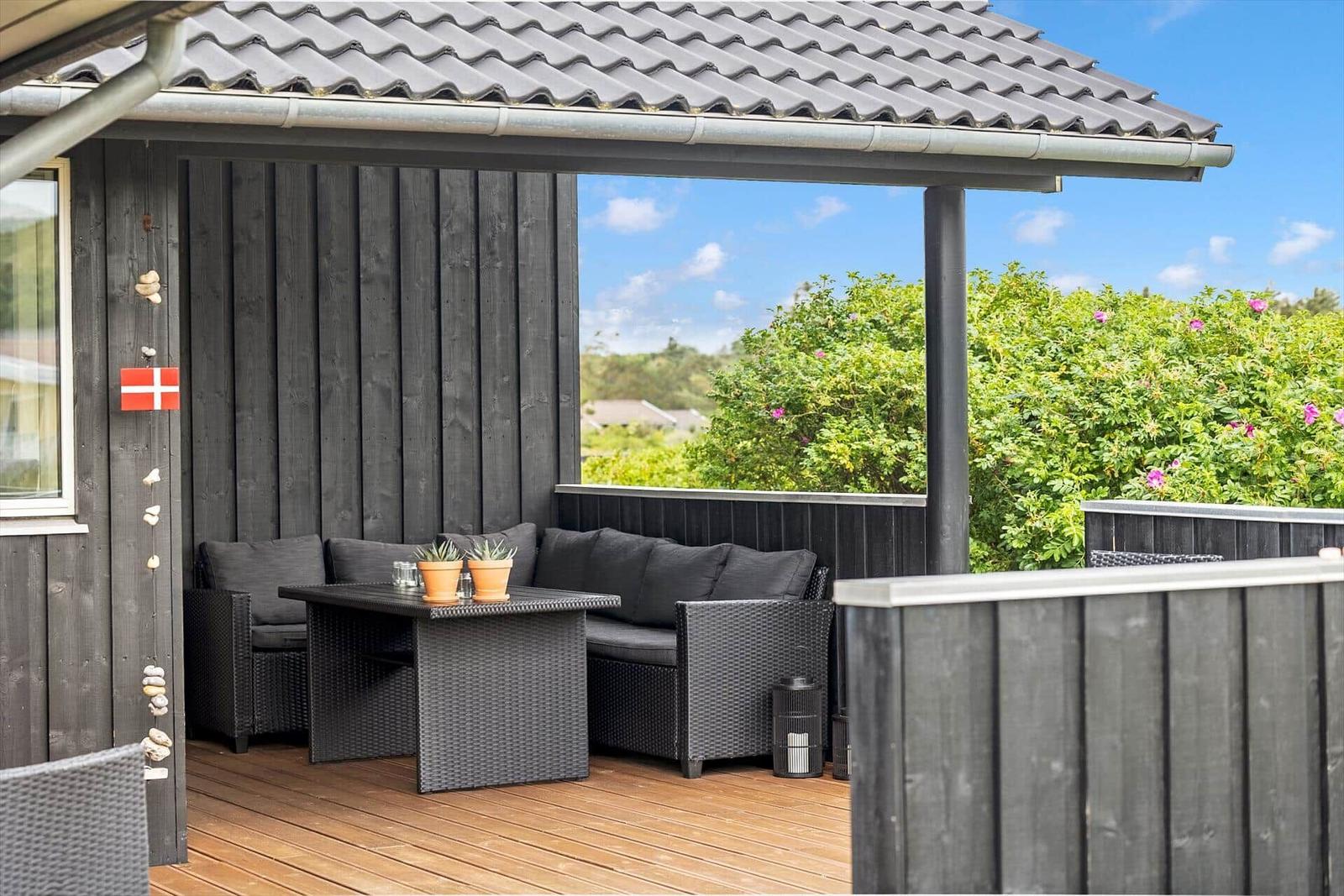 Terrasse mit Sitzgruppe, Tisch und Blick auf grüne Vegetation.