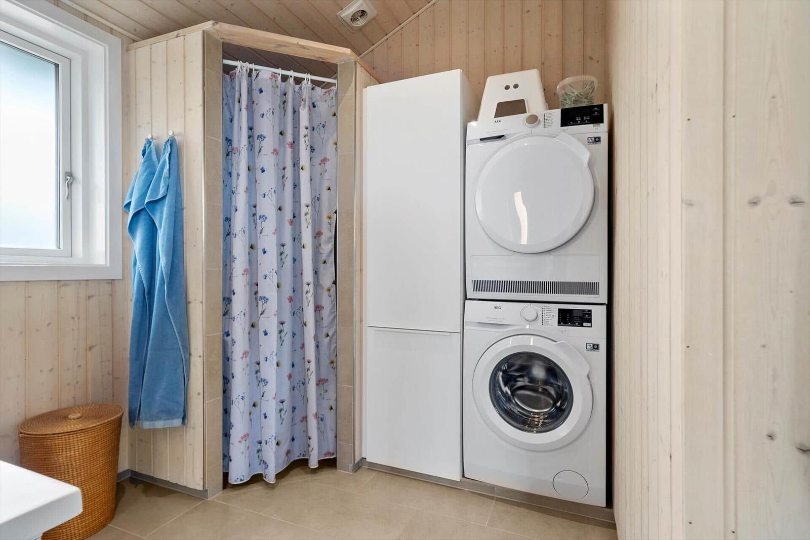 Wäscherei mit Waschmaschine und Trockner, Dusche mit Vorhang und blauer Handtuchhaken.
