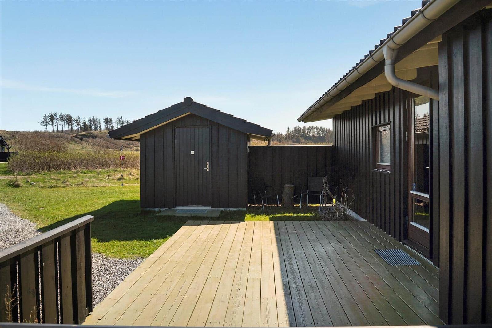 Holzterrasse mit Blick auf eine kleine Hütte und Grünland.
