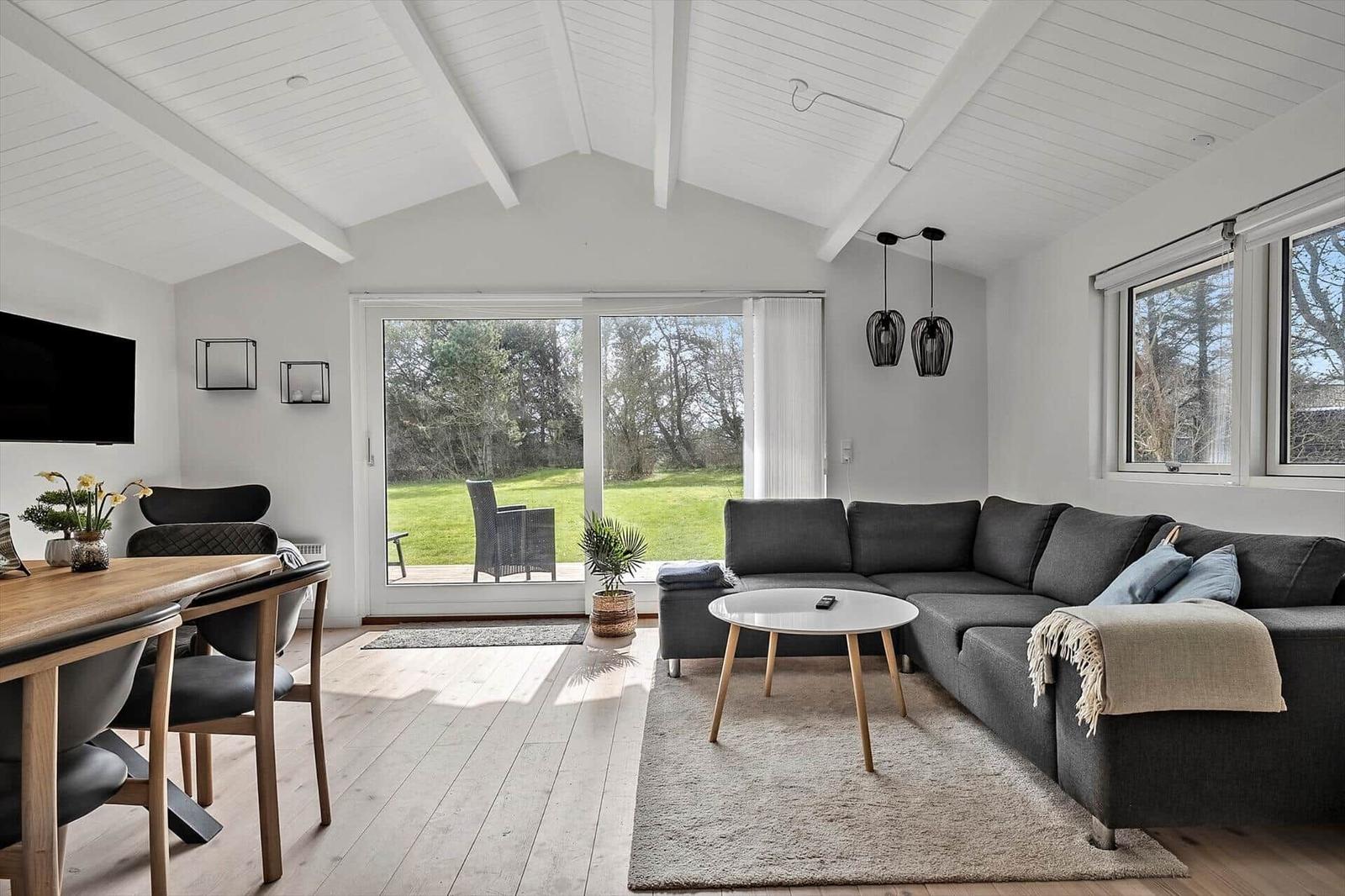 Wohnbereich mit Sofa, Tisch und Blick auf den Garten.