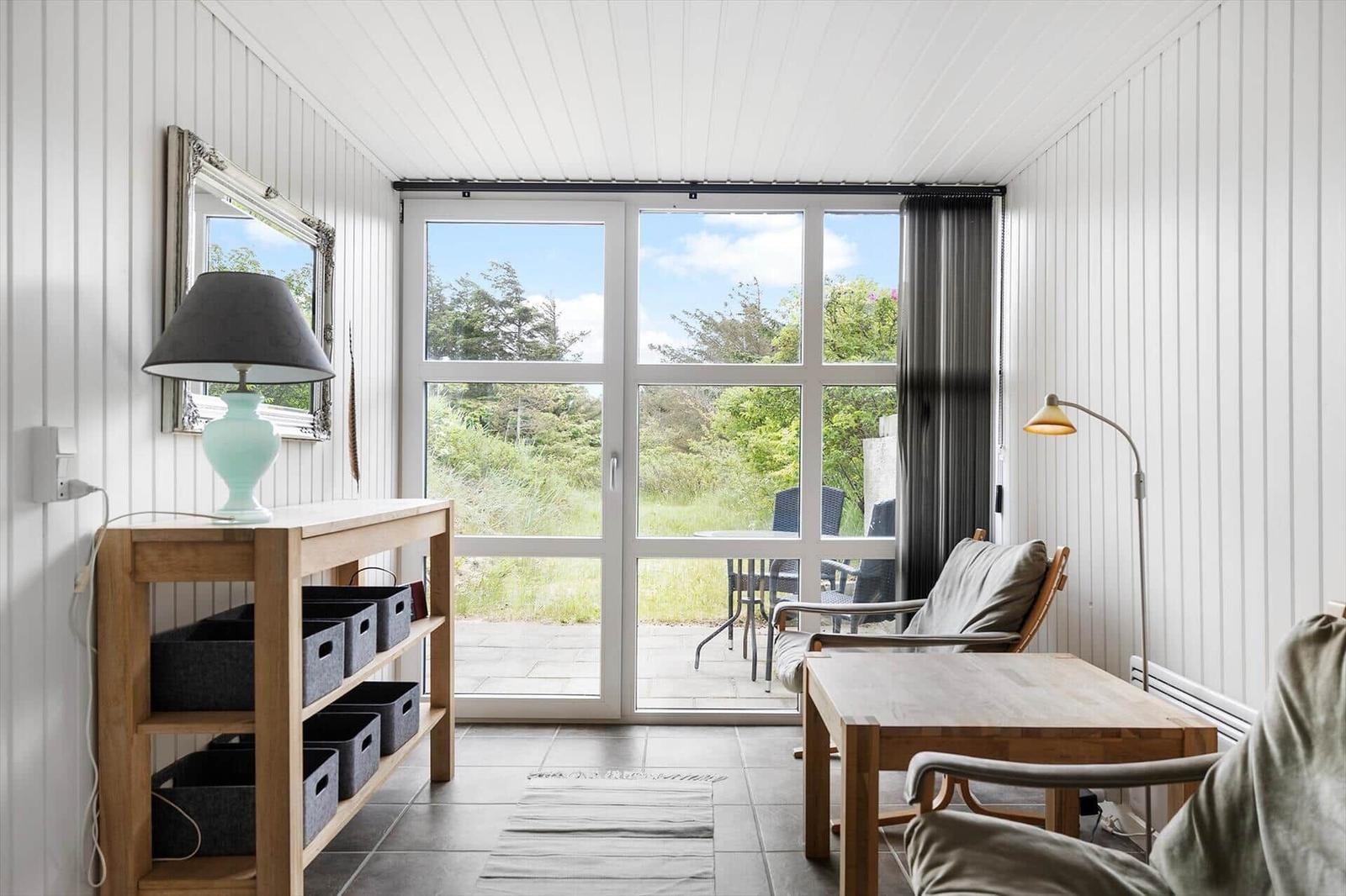 Room with wooden furniture, windows to the outdoor terrace, and wall mirror.