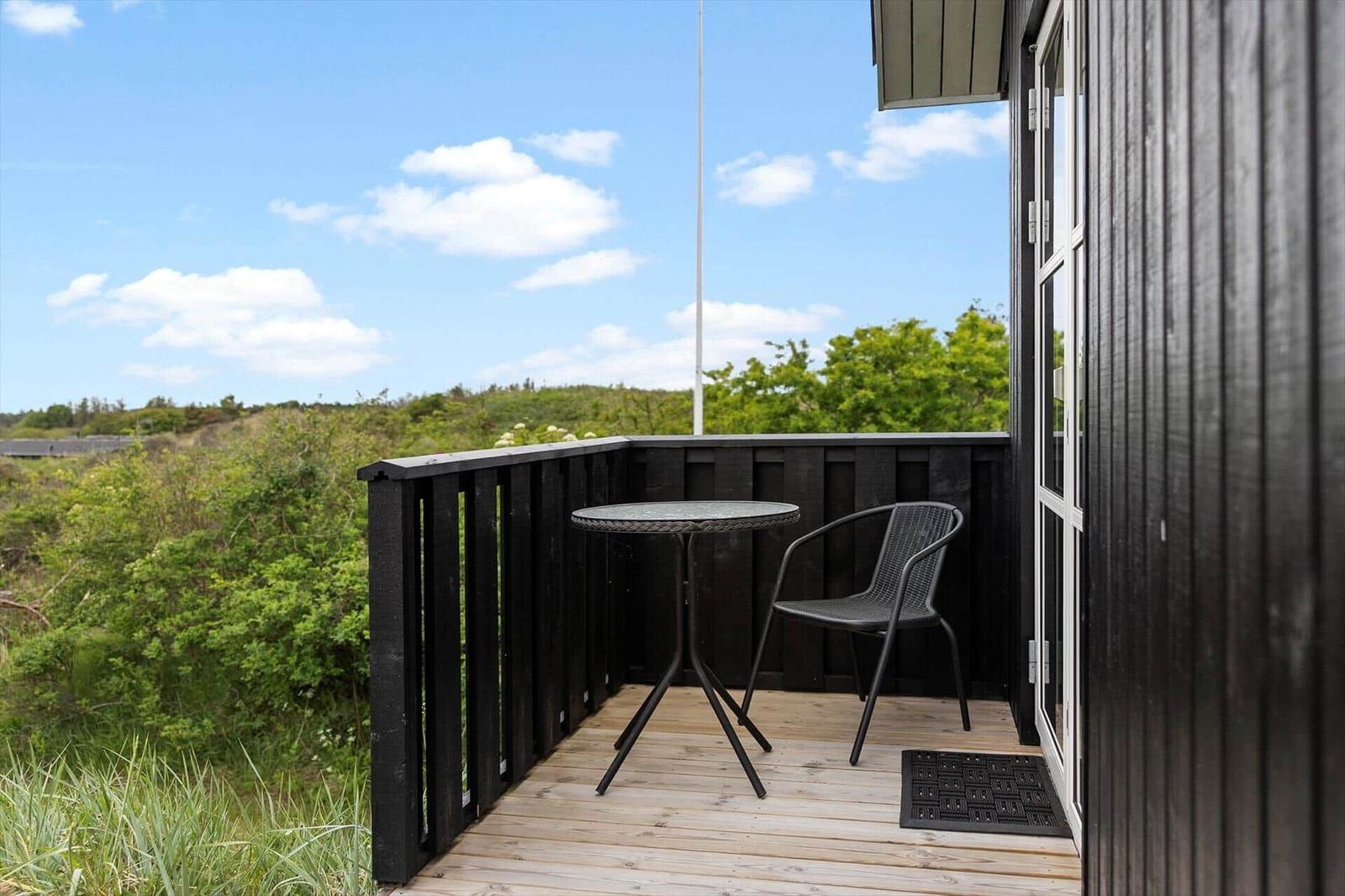 Deck with table and chair, view of green landscape and blue sky.