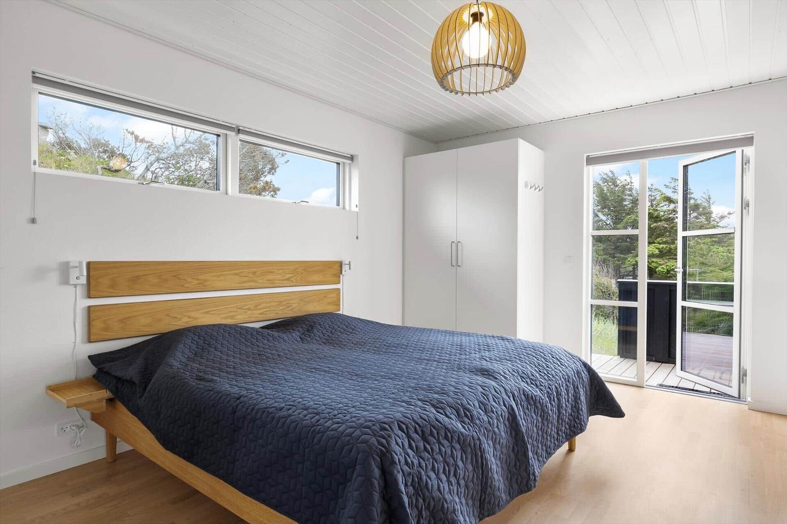 Bedroom with bed, wardrobe, and windows to the terrace.