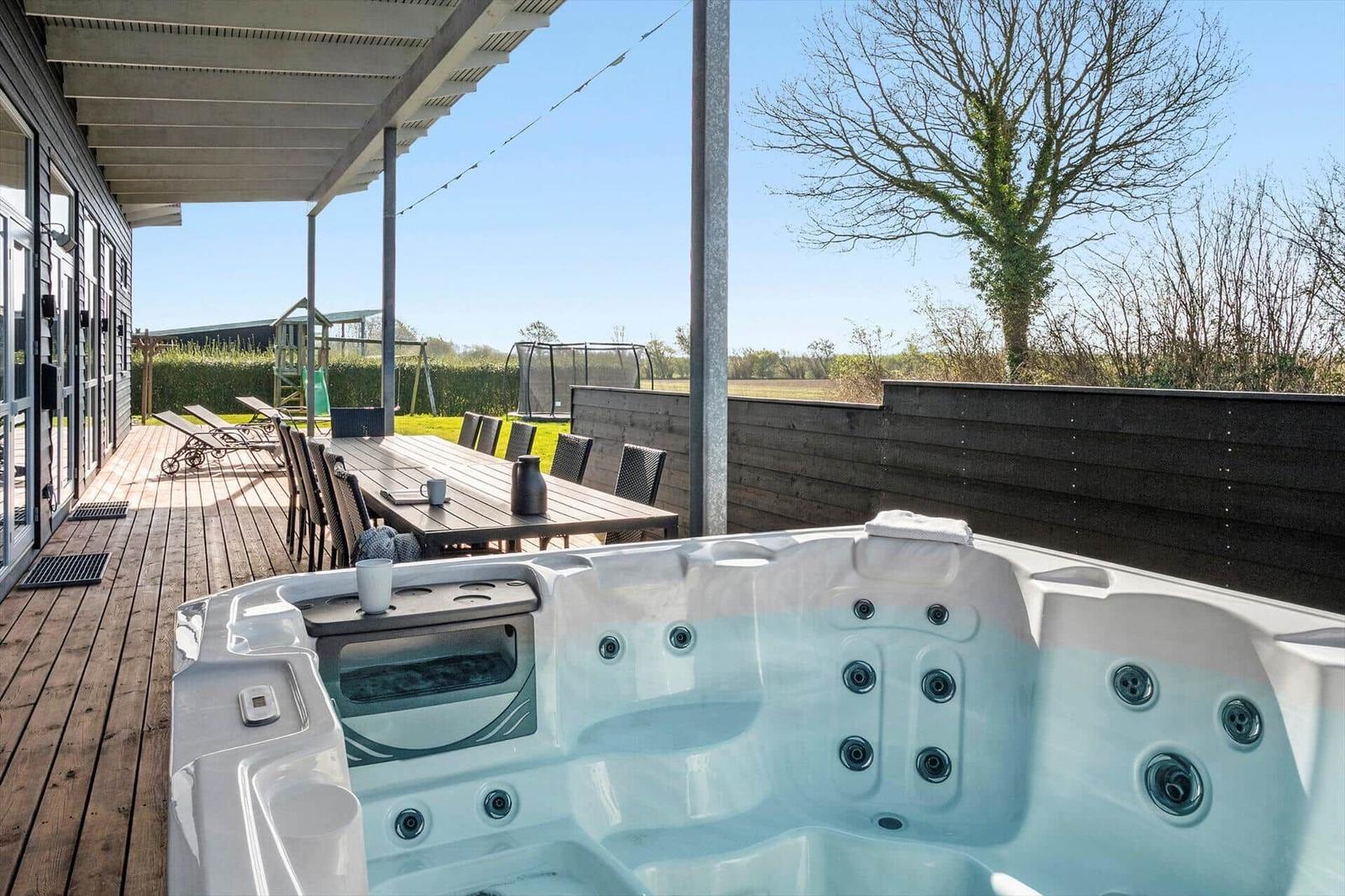Hot tub on terrace with seating and view of garden.