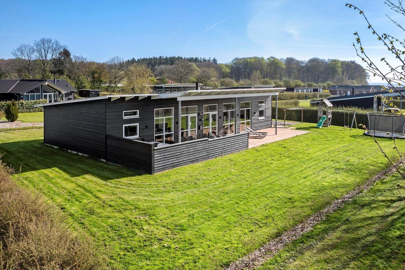 Modern wooden cabin with large garden and playground. Terrace with seating area.