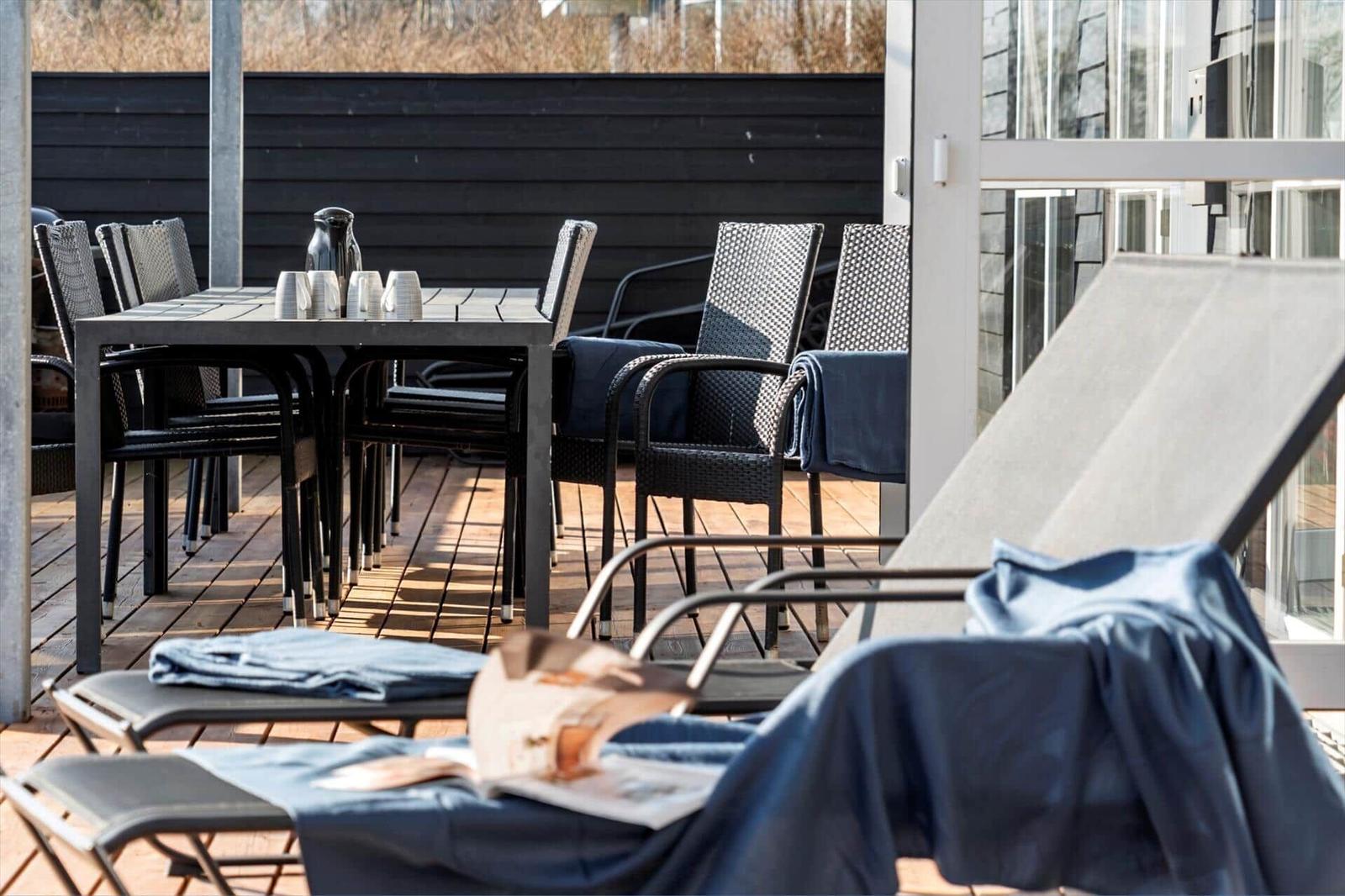 Terrace with table, chairs, and lounge chairs. Dark blue blankets are on them.