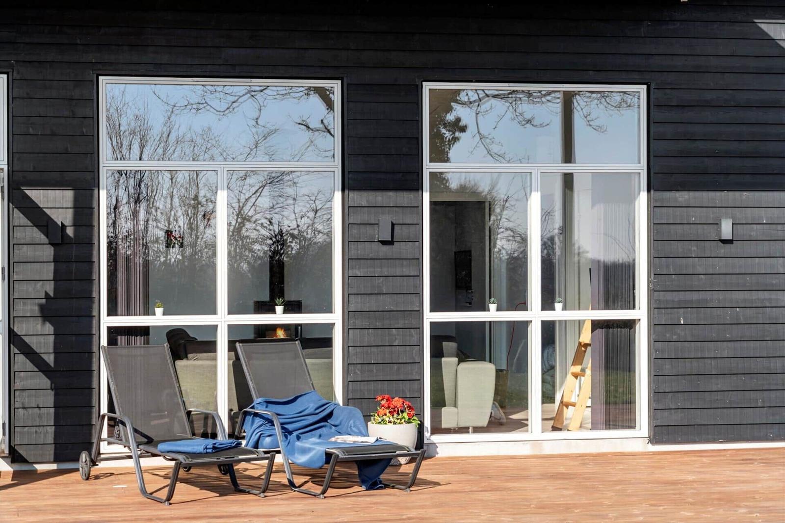 Deck with lounge chairs and view into living area through windows.