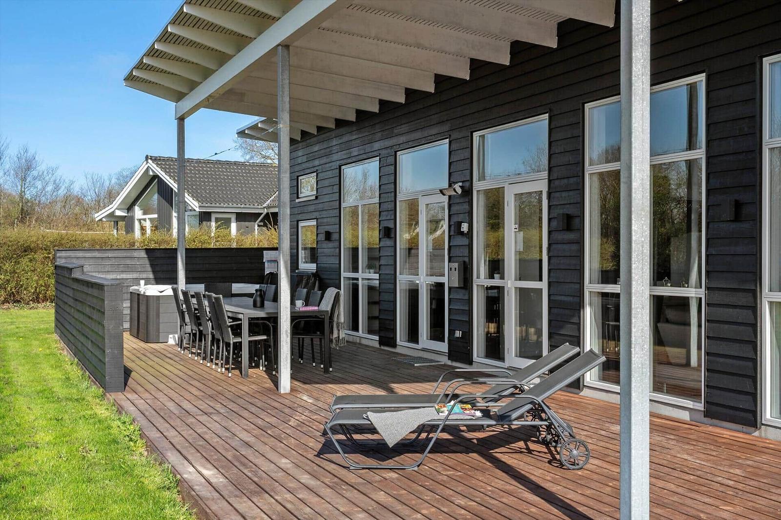 Deck with lounge chairs, table and chairs. Black wood siding and large windows.
