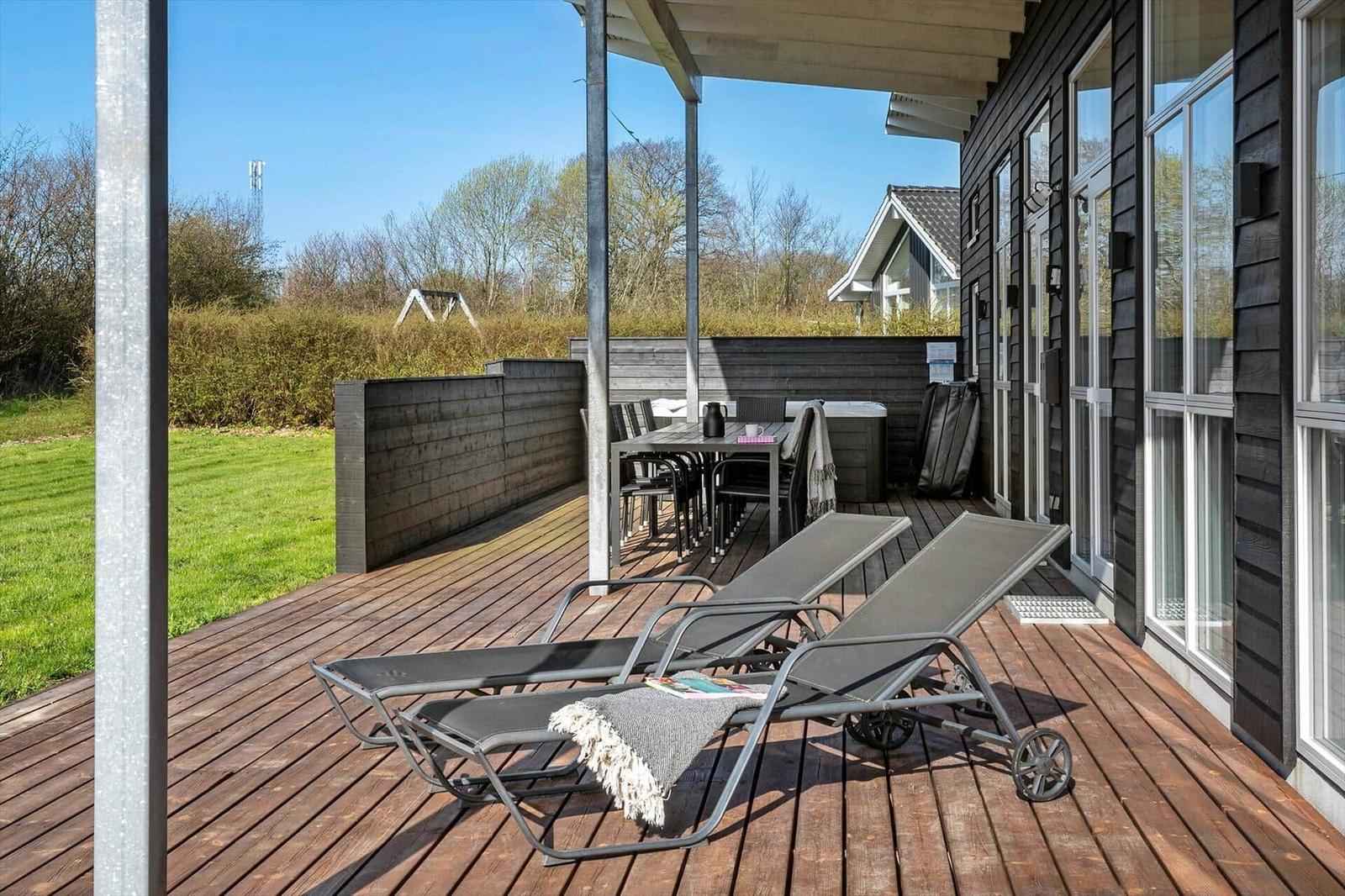 Deck with loungers, table and chairs. Backyard with lawn and fence.