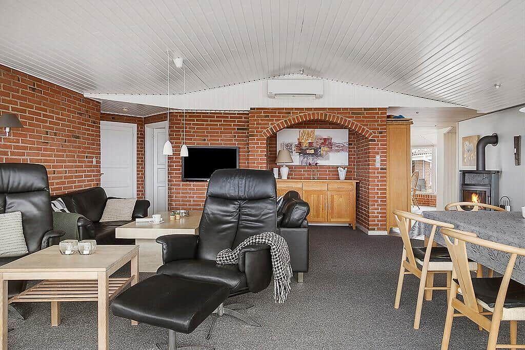 Wohn- und Essbereich mit Ledersofa, Kamin und Backsteinwand.