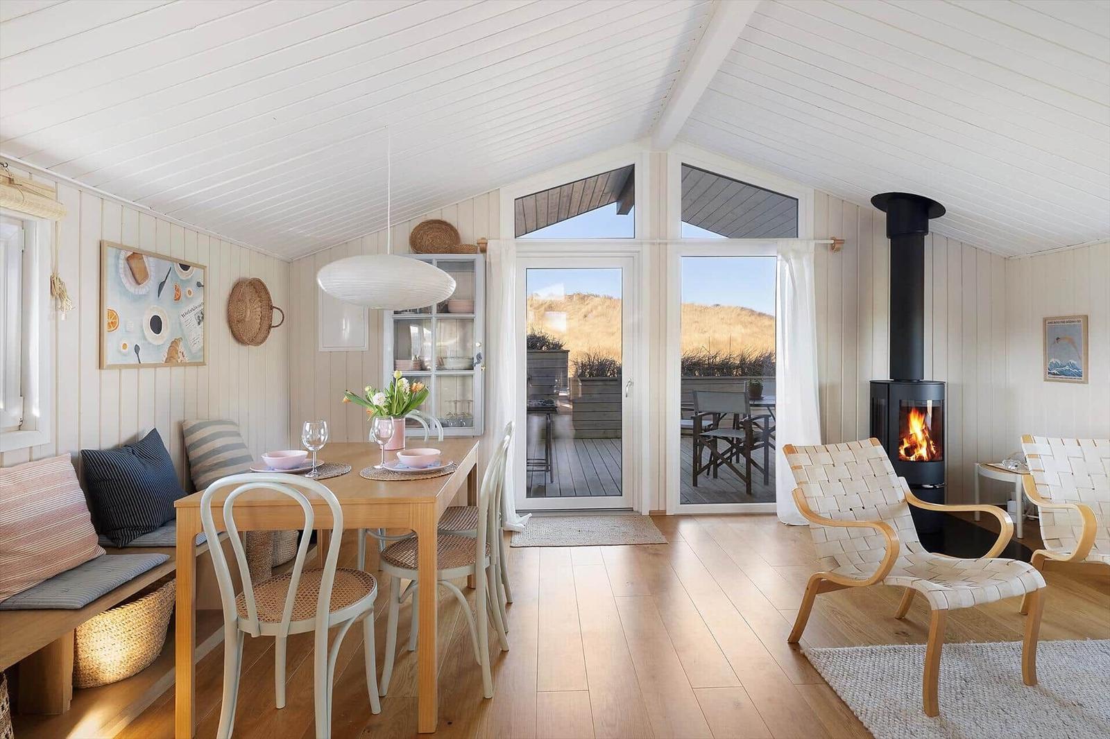 Dining area with table and chairs, a terrace, and a wood stove.