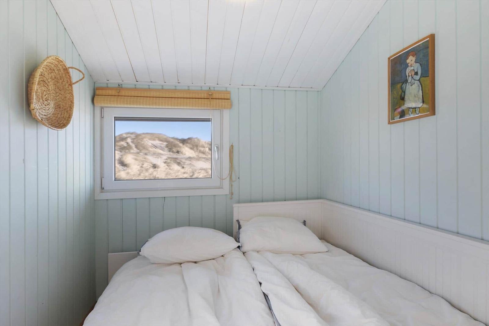 Bedroom with bed, window, and wall picture.