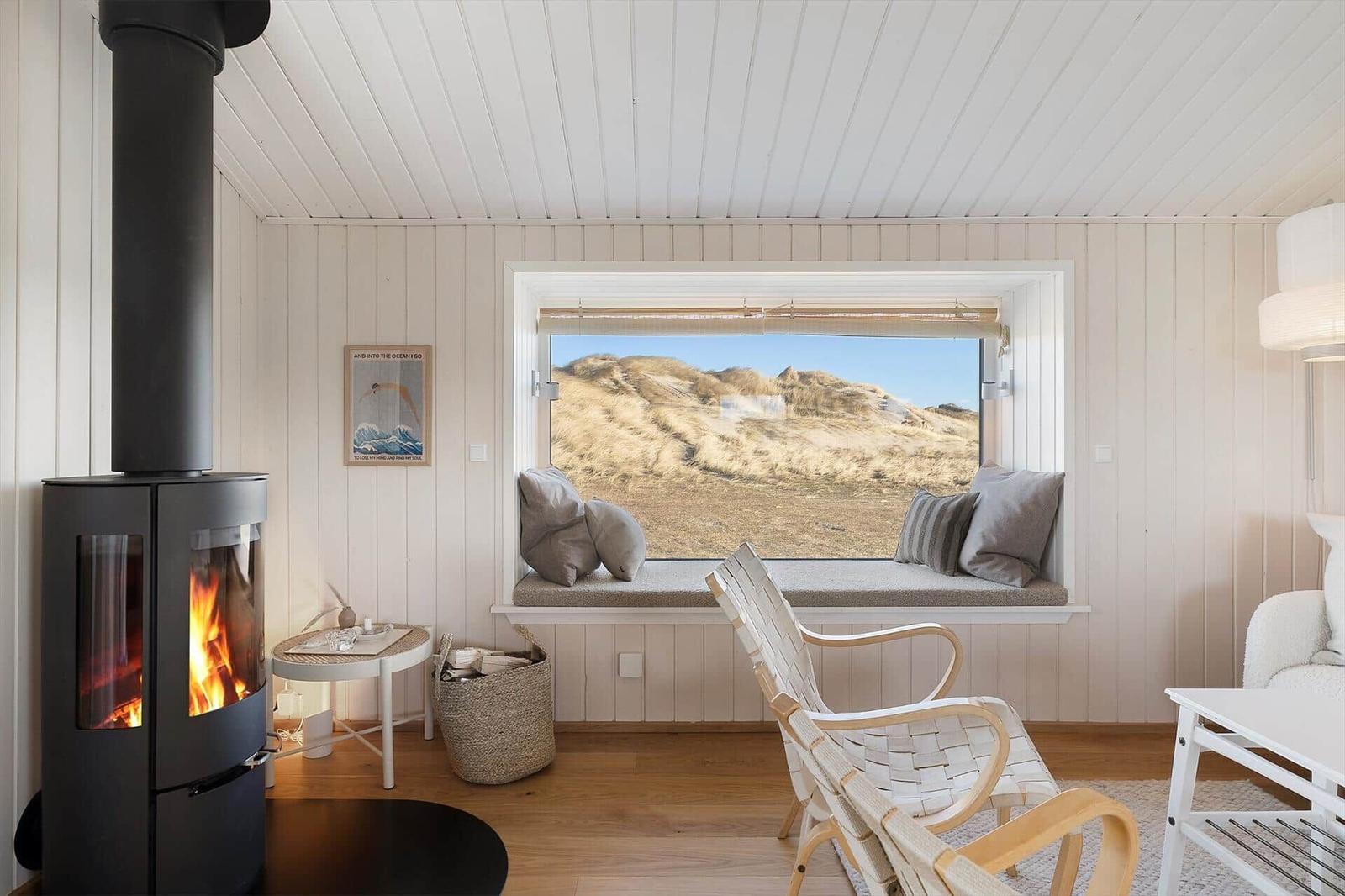 A room with fireplace, window seat, and view of dunes.