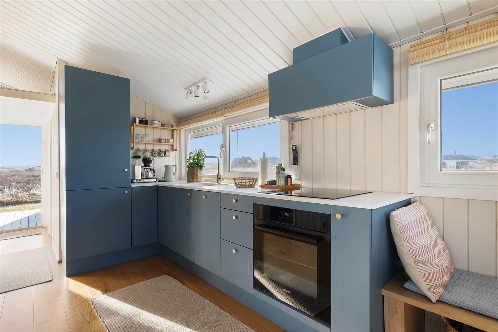 Kitchen with blue cabinets, windows, and built-in cooktop.